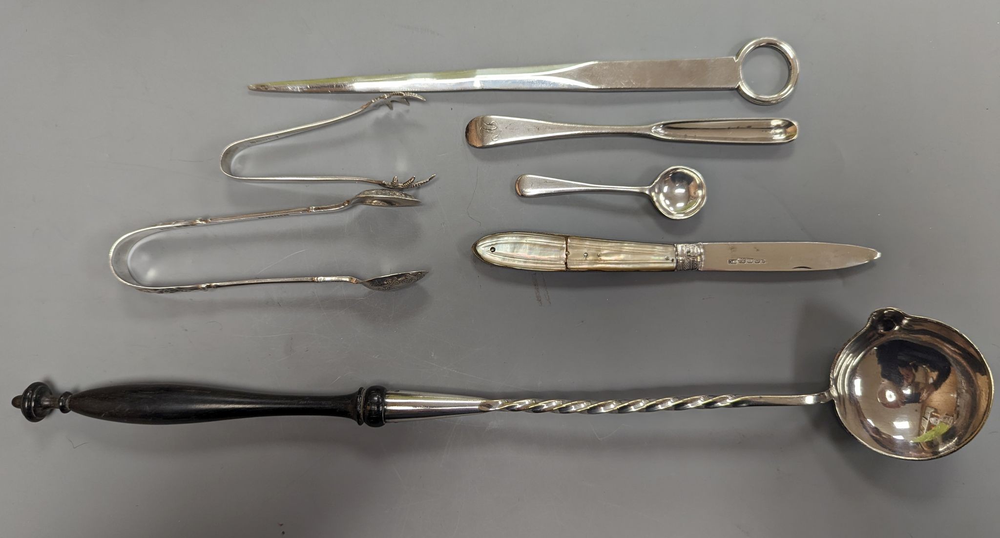 A George VI silver paper knife, London, 1937, a plated toddy ladle, two pairs of silver sugar tongs, damaged silver fruit knife and two other items.